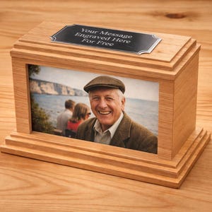 Könnte beinhalten: Holz-Foto-Urne mit rechteckiger Form und einem gerahmten Foto eines lächelnden Mannes. Die Urne hat eine dekorative Ober- und Unterseite sowie eine Metallplakette mit der Aufschrift "Your Message Engraved Here For Free".