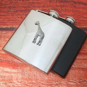 May include: A silver and black stainless steel hip flask with a pewter giraffe design.
