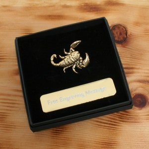May include: A gold-colored scorpion figurine in a black velvet box with a gold plaque that says "Free Engraving Message".