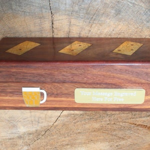 May include: A wooden box with a gold metal plate that says "Your Message Engraved Here For Free". The box has three gold dominoes on the top and a beer mug design on the front.