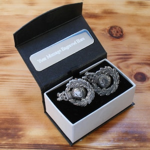 May include: A black gift box with a silver plaque that says "Your Message Engraved Here". The box is open and contains two silver cufflinks with a military design.