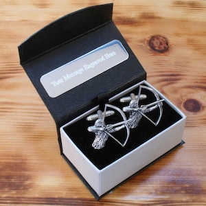 May include: Silver cufflinks in a black gift box. The cufflinks feature an archer with a bow and arrow design. The box has a white interior and a silver plate with the text "Your Message Engraved Here". The box is open, revealing the cufflinks.