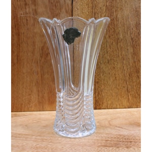 May include: A clear glass vase with a textured design. The vase has a wide mouth and a narrow base.