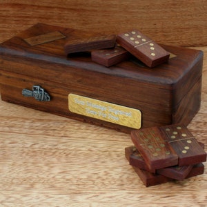 May include: A wooden box with a brass latch and a brass plaque that says "Your Message Engraved Here For Free". The box contains a set of wooden dominoes with brass dots.