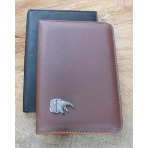 May include: Two leather-bound journals, one brown and one black, with a silver ant-eater charm on the brown journal.