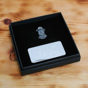 May include: A silver-colored pewter figurine of a person wearing a hat, in a black box with a silver plaque that reads "Thank you for everything you do.  Enjoy your day."