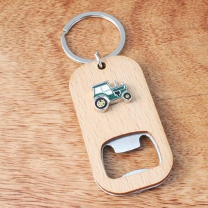 May include: A wooden bottle opener keychain with a green tractor charm. The keychain has a silver ring and a wooden handle with a bottle opener.