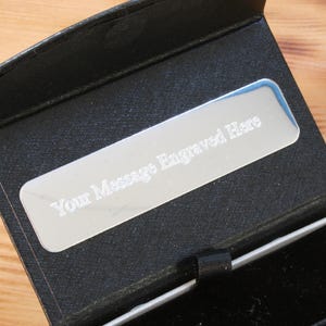May include: A black gift box with a silver plaque that reads "Your Message Engraved Here".