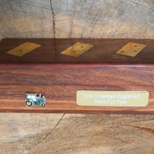 May include: A wooden box with a gold tractor design on the front. The box has a brass plaque that says "Your Message Engraved Here For Free".