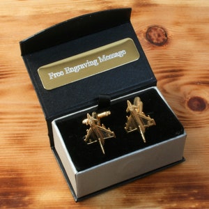Puede incluir: Gemelos de oro en forma de avión de combate, en una caja de regalo negra y plateada con una placa dorada que dice "Mensaje de grabado gratuito".