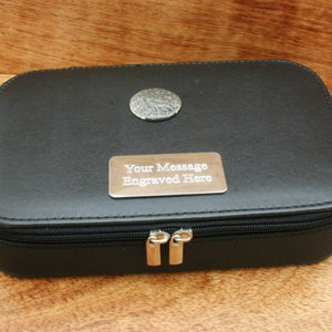 May include: Black leather travel case with a silver zipper and a silver engraved plate that says "Your Message Engraved Here".