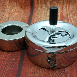 Puede incluir: Un cenicero cromado con tapa giratoria y diseño de hada. El cenicero tiene un pequeño cuenco interior extraíble.