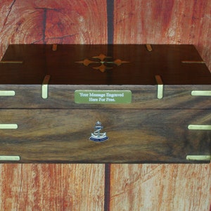 May include: A dark wood box with brass accents and a brass plaque that says "Your Message Engraved Here For Free." The box has a Royal Navy emblem on the front.