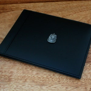 May include: A black leather journal with a silver Egyptian scarab beetle design on the front cover.