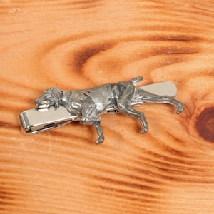 May include: Silver tie clip featuring a detailed sculpture of a hunting dog in a running pose.