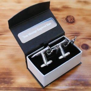 May include: A black gift box with a silver cufflink set inside. The box has a silver plaque that says "Your Message Engraved Here".