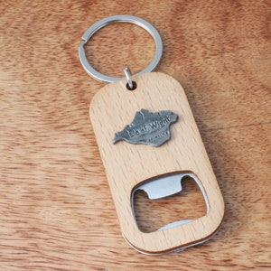 May include: A wooden bottle opener keychain with a metal charm shaped like the Isle of Wight. The charm has the words "Isle of Wight" and "England" on it.
