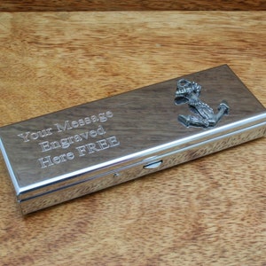Könnte beinhalten: Ein silbernes Zigarettenetui mit einem Anker-Anhänger. Das Etui trägt eine Inschrift mit dem Text "Your Message Engraved Here FREE".