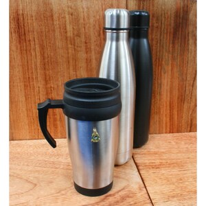 May include: A silver travel mug with a black lid and handle, next to two stainless steel water bottles, one silver and one black.