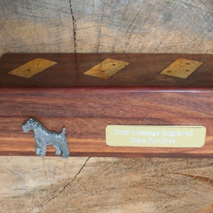 Puede incluir: Una caja de madera con una placa de latón que dice "Su mensaje grabado aquí gratis". La caja tiene tres dominós incrustados y una figurita de perro de peltre.