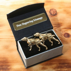 May include: A pair of gold-coloured cufflinks in the shape of a running dog, presented in a black gift box with a silver lining. The box has a gold plaque that reads "Free Engraving Message".