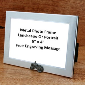 May include: Silver metal photo frame with a tractor figurine on the bottom. The frame is 6 inches by 4 inches and can be used for landscape or portrait photos. The text on the frame reads "Metal Photo Frame Landscape Or Portrait 6" x 4" Free Engraving Message".