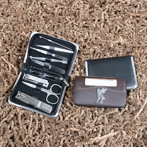 May include: A black manicure set with stainless steel tools, including clippers, scissors, and files. Also, a brown and black case with a fairy emblem and a black card case.