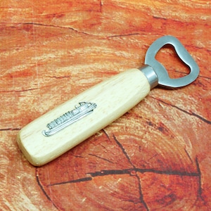 Puede incluir: Un abridor de botellas de madera con un abridor de metal y un diseño de barco plateado en el mango.