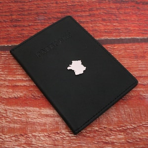 May include: Black leather passport holder with the word "PASSPORT" embossed on the front and a silver outline of France.