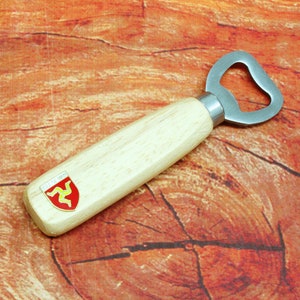 May include: A wooden bottle opener with a metal opener and a red and yellow emblem on the handle. The emblem features three legs.