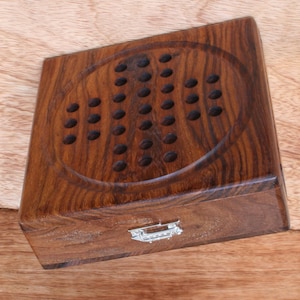 Könnte beinhalten: Ein Holzspielbrett mit einem runden Spielbereich und einem Klappdeckel. Das Brett ist aus dunklem Holz mit natürlicher Maserung.