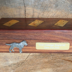 May include: A wooden box with a hinged lid, featuring three inlaid squares of wood with a diamond pattern. The box has a silver dog figurine on the front and a brass plaque that reads "Your Message Engraved Here For Free".