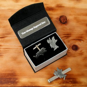May include: A black gift box with a silver plate that says "Your Message Engraved Here". The box contains two silver cufflinks and a tie clip, all shaped like a map of Scotland.