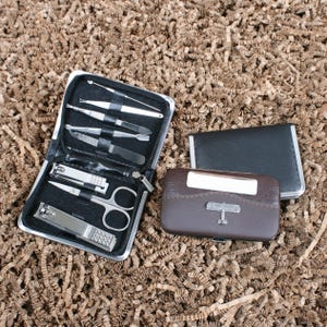 May include: A black zippered manicure kit with stainless steel tools, including nail clippers, scissors, and files. A brown leather case with a silver airplane emblem and a black card holder are also present.