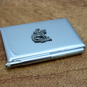 Op de afbeelding: Een zilveren metalen visitekaartjeshouder met een reliëf van een ridder te paard in tin.