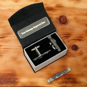 May include: A black gift box with a silver plate that says "Your Message Engraved Here". The box contains a pair of silver cufflinks and a tie clip, all featuring a racing car design.