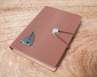 May include: A brown leather journal with a silver sailboat charm and a brown leather strap closure.