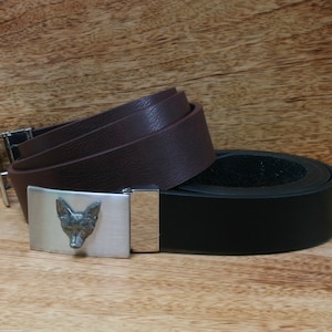 May include: Two leather belts with a silver fox head buckle. The top belt is brown and the bottom belt is black.