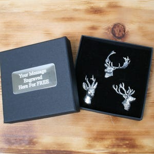 May include: A black gift box with a silver plaque that says "Your Message Engraved Here For FREE". The box is open and shows three silver deer head cufflinks in a black velvet box.