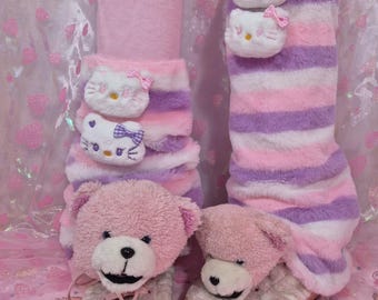 May include: Pink and purple striped fluffy leg warmers with a pink teddy bear and a white Hello Kitty face attached to each leg warmer.
