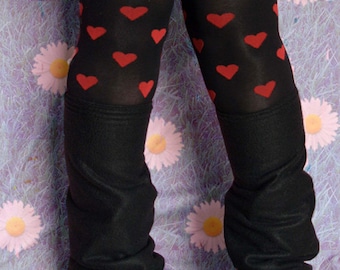 Può includere: Collant neri con motivi a forma di cuore rossi e stivali neri con plateau. I collant sono piegati al ginocchio per creare un effetto leggings. Gli stivali hanno una suola spessa con plateau e un design nero con lacci.