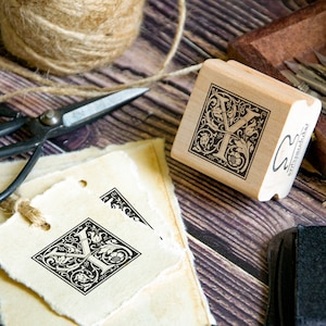 May include: A wooden stamp with a decorative letter Y in a square frame. The stamp is made by "Artpark Ink".
