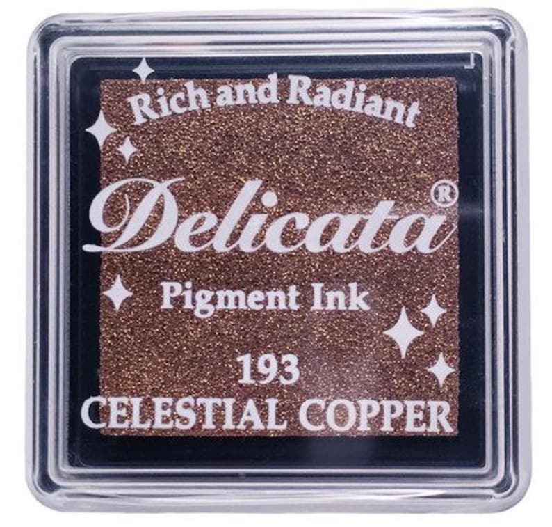May include: A square ink pad with a metallic copper color. The ink pad is labeled "Delicata Pigment Ink" and "Celestial Copper" with the number "193". The ink pad is in a clear plastic case.
