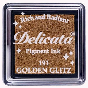 May include: A gold ink pad with the text "Rich and Radiant Delicata Pigment Ink 191 GOLDEN GLITZ" on the front.