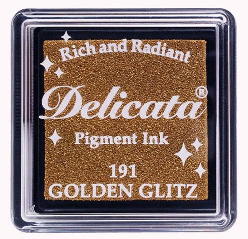 May include: A gold ink pad with the text "Rich and Radiant Delicata Pigment Ink 191 GOLDEN GLITZ" on the front.