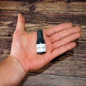 May include: A small black bottle of Memento Luxe Ink in the color "Tuxedo Black". The bottle is labeled "Dye Ink" and "Acid Free".