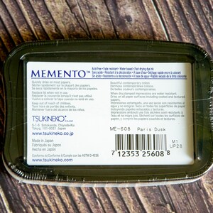 May include: Memento Paris Dusk dye ink pad, acid-free, fade resistant, water-based, fast drying, and dries on most papers. The ink pad is packaged in a black plastic container with a barcode and the text "ME-608 Paris Dusk".
