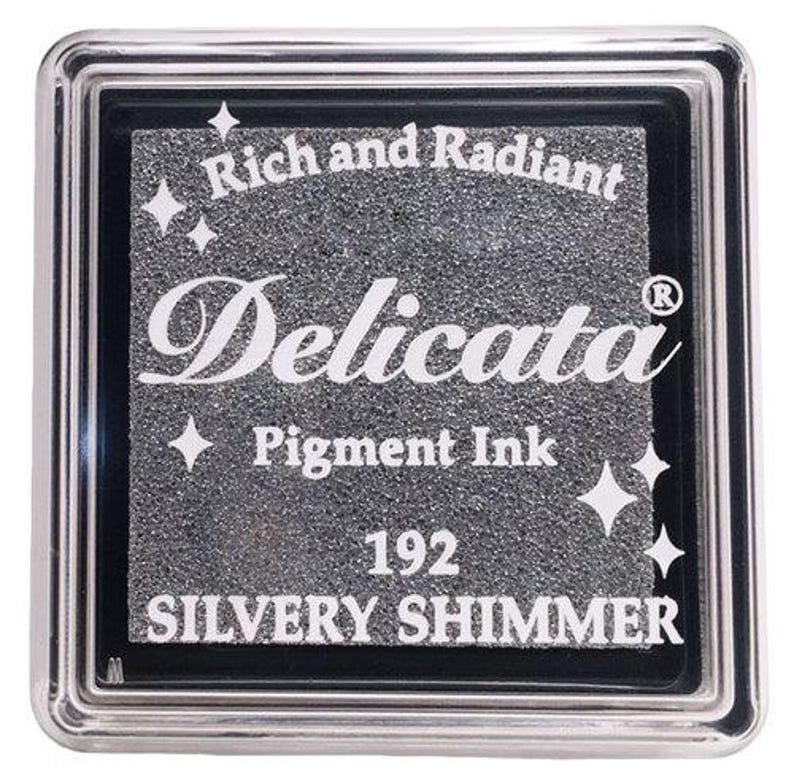 May include: A silver ink pad with the text "Rich and Radiant Delicata Pigment Ink 192 SILVERY SHIMMER" and a small star design.
