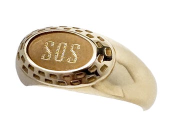 May include: A gold ring with an oval face. The face of the ring has the letters "SOS" engraved in the center. The ring has a textured border around the face.