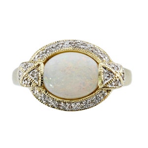 May include: A gold ring with a white opal gemstone surrounded by a halo of small diamonds.